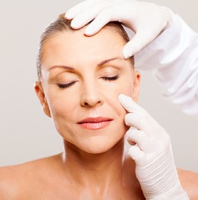 doctor examining mid age woman skin before cosmetic surgery
